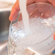 A person holds a cup under tap water and lets the water spill out.